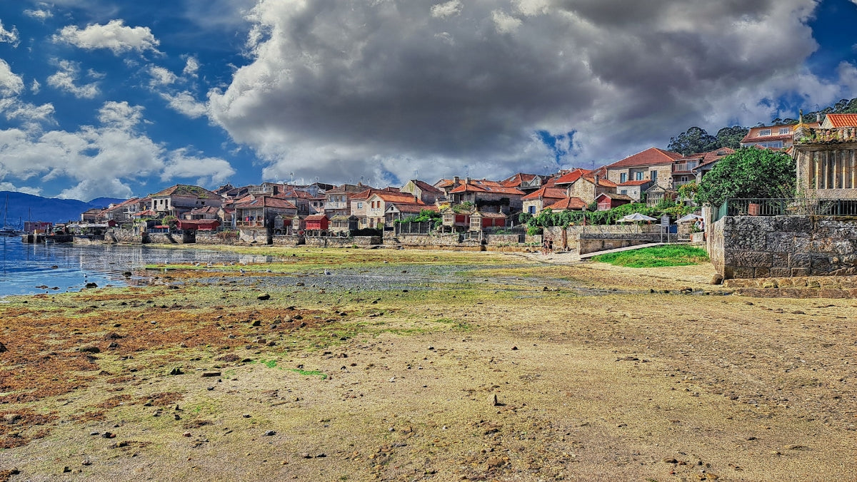 Coastal town with buildings on a hill overlooking water.