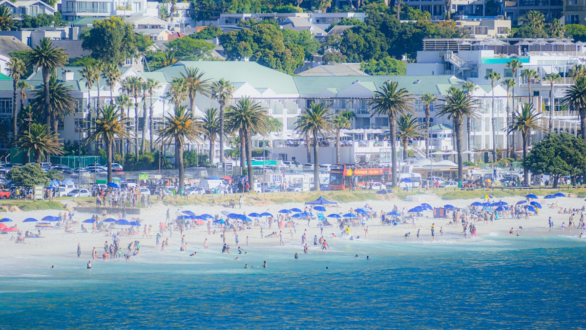 Crowded beach with umbrellas and buildings in background