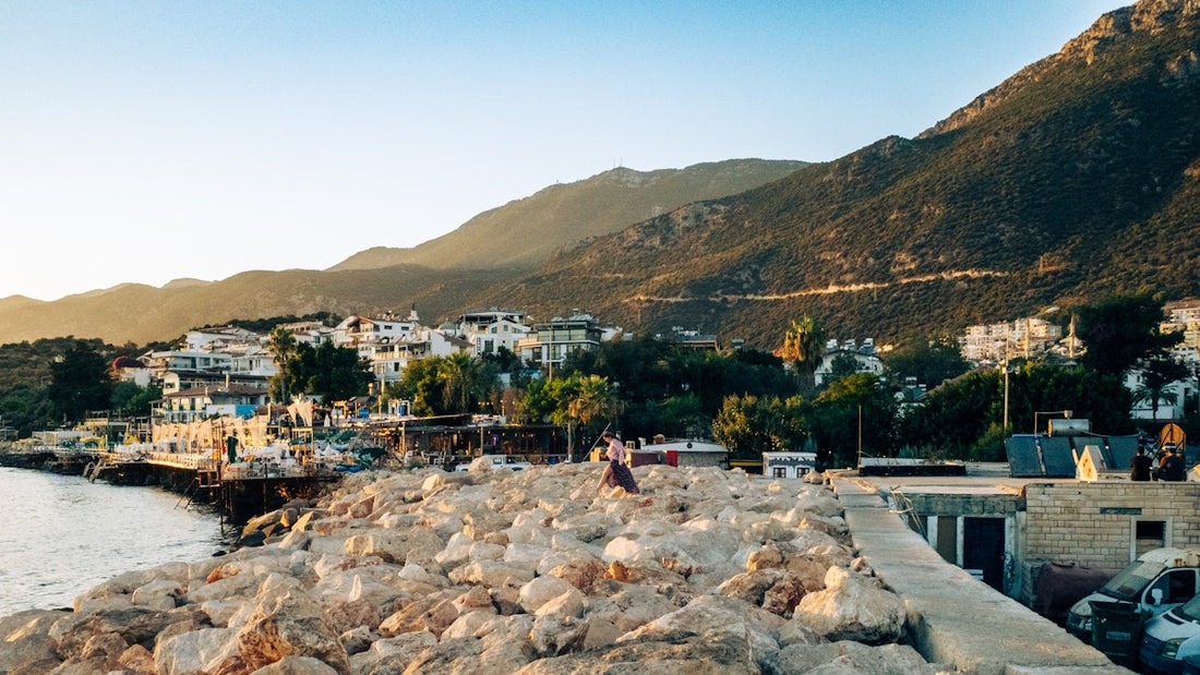 Coastal town nestled beside mountains under clear sky.