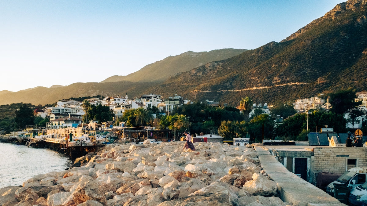 Coastal town nestled beside mountains under clear sky.