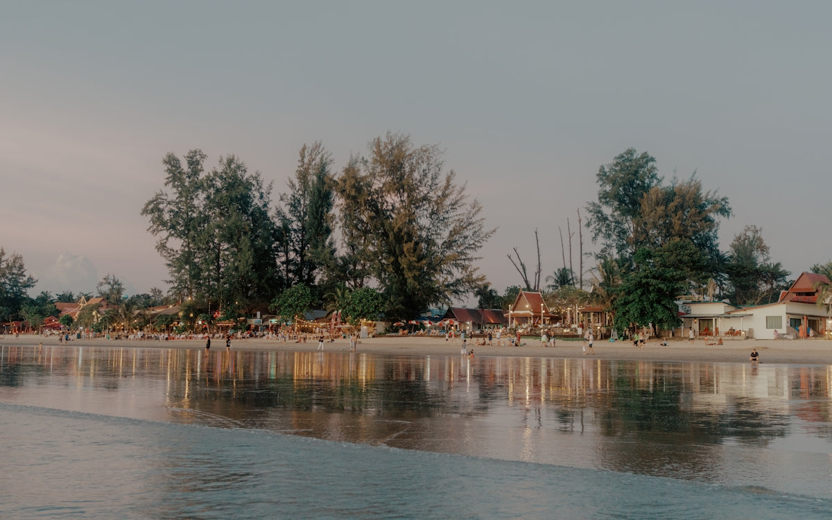 Calm ocean reflecting trees and buildings on shore