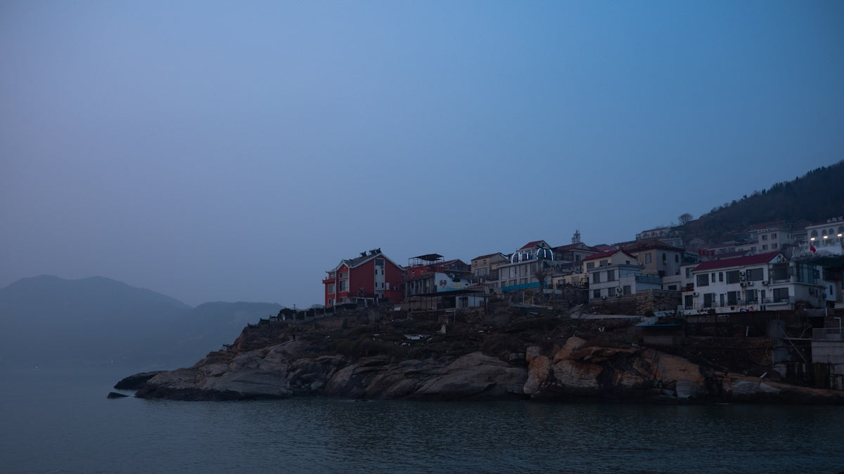 Coastal village on a rocky cliff at dusk.