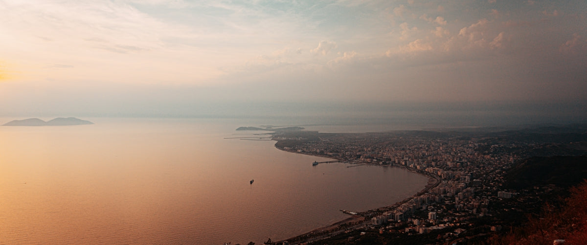 Coastal city skyline at sunset with calm ocean water