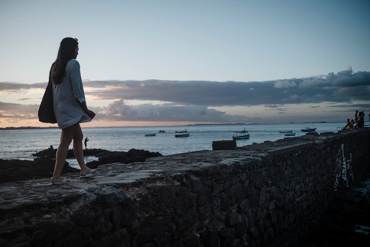 Woman walking by the ocean at sunset
