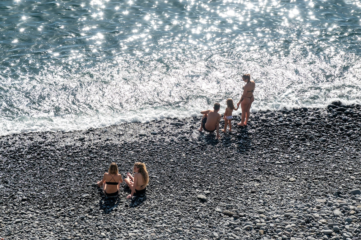 People relaxing on a pebble beach by the ocean