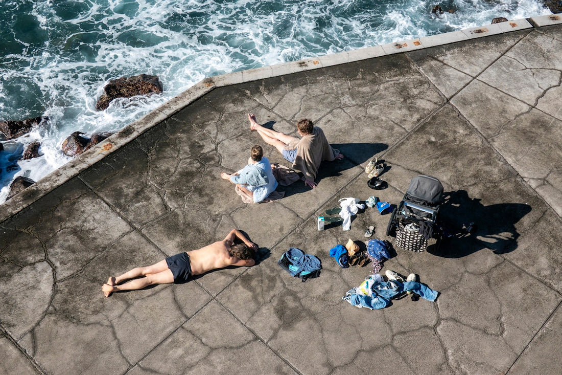 People relaxing on a concrete surface by the ocean.